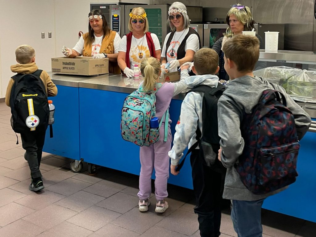 From left: While dressed in their 70’s clothes for National School Lunch Week , Hilltop Elementary Cafeteria Manager Johnnie Wayt along with cooks Tina Yoho, Missy Francis and Shasta Lucey serve students  in the school’s cafeteria.