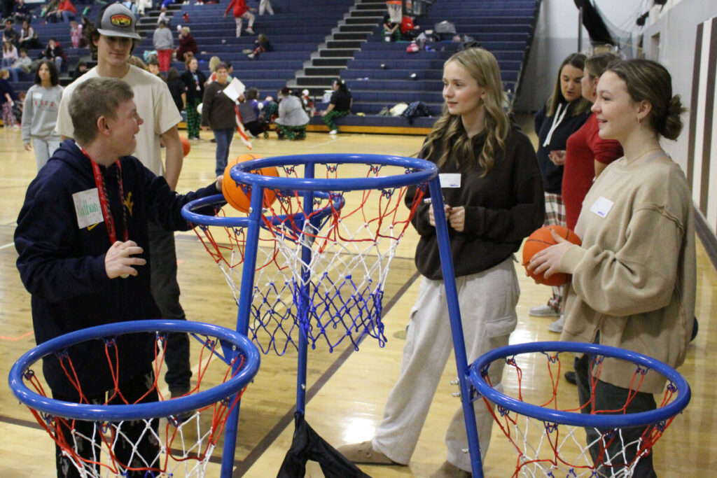 Special Olympics athlete Nathan slam dunks a basketball while peer tutors cheer for him.