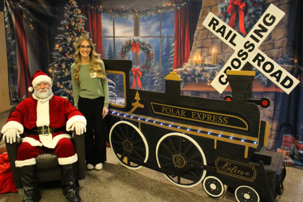 JMHS senior Hailey Jones poses with Santa Claus and the wooden replica of The Polar Express steam engine she made in her CTE class for the Special Olympics event.